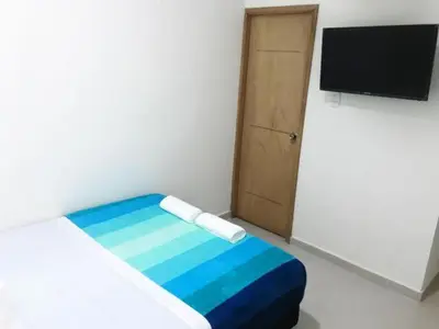 a room with a bed and a television and a door at Hostal Lumar in Barranquilla
