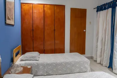 a bedroom with two beds and a wooden cabinet at Hotel Veleros Cartagena in Cartagena de Indias