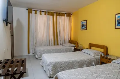 a hotel room with three beds and a window at Hotel Veleros Cartagena in Cartagena de Indias