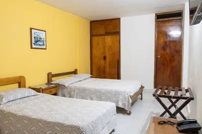 two beds in a room with yellow walls at Hotel Veleros Cartagena in Cartagena de Indias