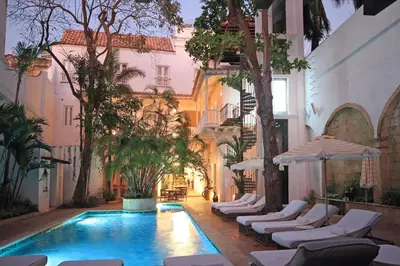 a courtyard with a swimming pool with chairs and umbrellas at Casa Pestagua Relais Châteaux in Cartagena de Indias