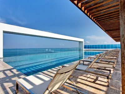 a swimming pool with chaise lounge chairs on a building at Las Americas Torre Del Mar in Cartagena de Indias