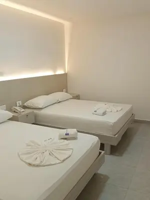 two beds in a hotel room with white walls at Hotel San Sebastian Real in Cartagena de Indias