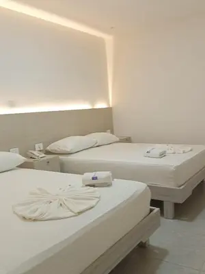 two beds in a hotel room with white walls at Hotel San Sebastian Real in Cartagena de Indias