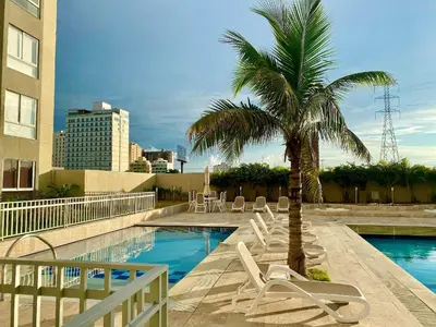 a palm tree and lounge chairs next to a swimming pool at Apartamentos Oceana - Cerca al Buenavista by SOHO in Barranquilla