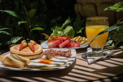 a table with two plates of food and a glass of orange juice at Hotel Casa La Fe in Cartagena de Indias