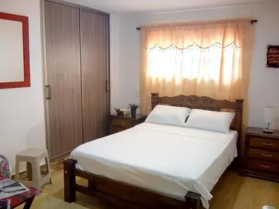 a bedroom with a large white bed with a window at Hostal Casa de Barajas in Cartagena de Indias