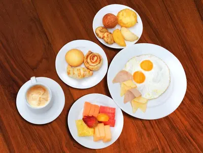 four plates of breakfast food on a wooden table at Hotel Barranquilla Plaza in Barranquilla