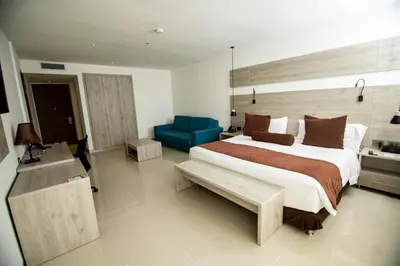 a bedroom with a large bed and a blue chair at Hotel Barranquilla Plaza in Barranquilla