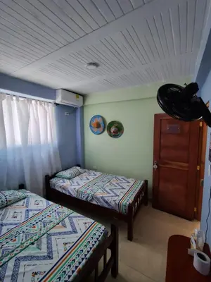 a room with two beds and a dresser in it at Milimar Hostal in San Onofre