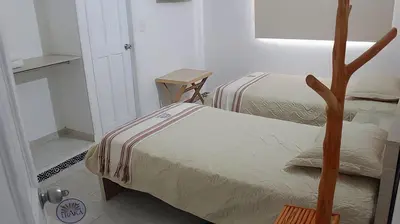a bedroom with two beds and a table and a door at Hotel Iraka Zenu in Sincelejo