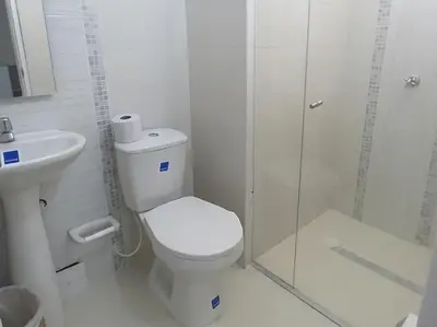a white bathroom with a toilet and a shower at Hotel Iraka Zenu in Sincelejo