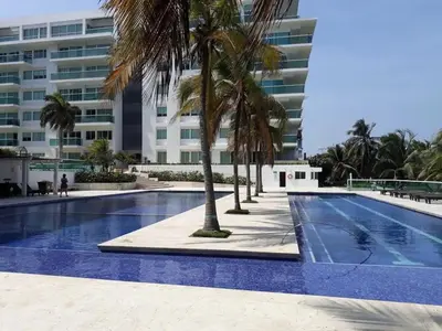 a swimming pool with palm trees in front of a building at Cartagena la Boquilla amobaldo vista directa al mar a pocos pasos de playa in Santa Barbará