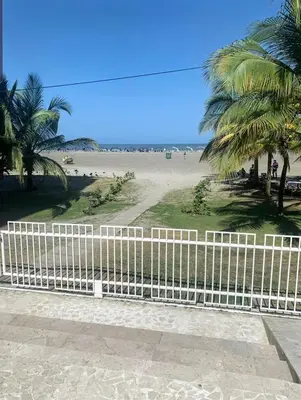 a white fence next to a beach with palm trees at Cartagena la Boquilla amobaldo vista directa al mar a pocos pasos de playa in Santa Barbará