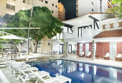 a swimming pool with white chairs and a building at Santorini Villas Santa Marta in Santa Marta