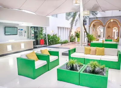 a lobby with green chairs and yellow pillows at Hotel Santorini Resort in Santa Marta