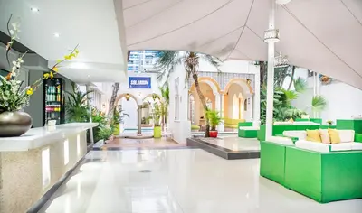 a lobby with green and white furniture and plants at Hotel Santorini Resort in Santa Marta