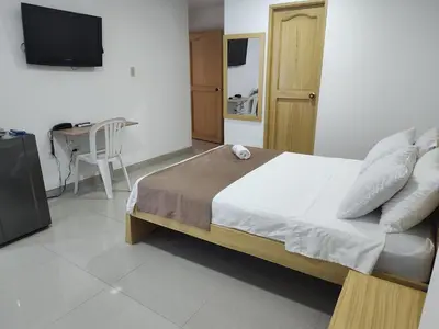 a bedroom with a bed and a table and a television at Hotel Ginebra Sincelejo in Sincelejo