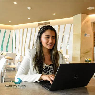 a woman sitting at a table using a laptop computer at Hotel Barlovento in Cartagena de Indias