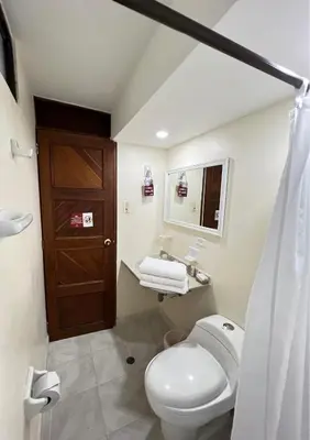 a bathroom with a toilet and a wooden door at Hotel Casa Ballesteros in Barranquilla