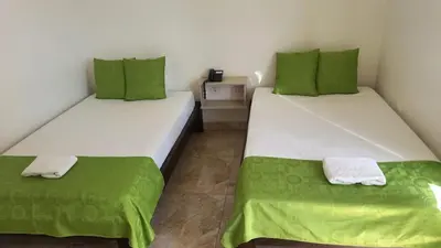 two beds in a room with green and white at Perla De La Sabana in Corozal