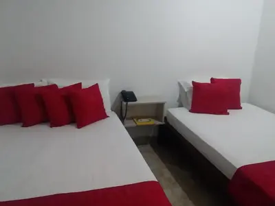 two beds with red pillows in a room at Perla De La Sabana in Corozal