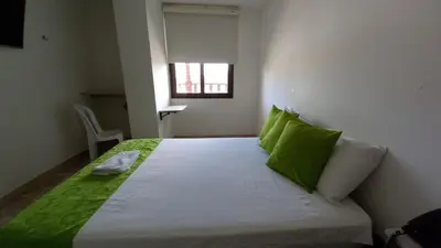 a bedroom with a bed with green pillows and a window at Perla De La Sabana in Corozal