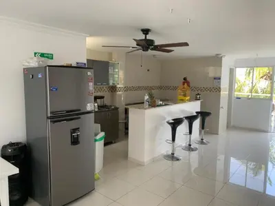 a kitchen with a refrigerator and a counter with stools at Hotel West Plaza in Santa Marta