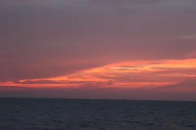 a sunset over the ocean with a cloudy sky at Hotel Puntanorte in Tintipan Island