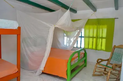 a bedroom with a canopy bed and a chair at Hotel Puntanorte in Tintipan Island