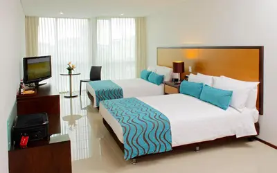 a hotel room with two beds and a television at Estelar Apartamentos Barranquilla in Barranquilla