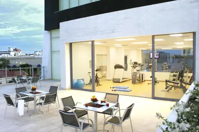 a balcony with tables and chairs and a gym at Estelar Apartamentos Barranquilla in Barranquilla