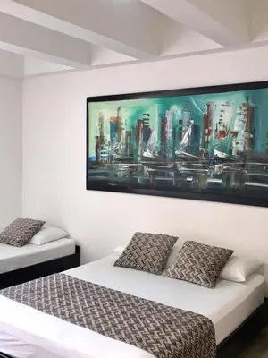a bedroom with two beds and a painting on the wall at Apartamentos Cartagena Caribe Suite in Cartagena de Indias