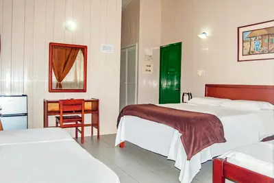 a bedroom with two beds and a table and a chair at Hotel Nitana in Coveñas