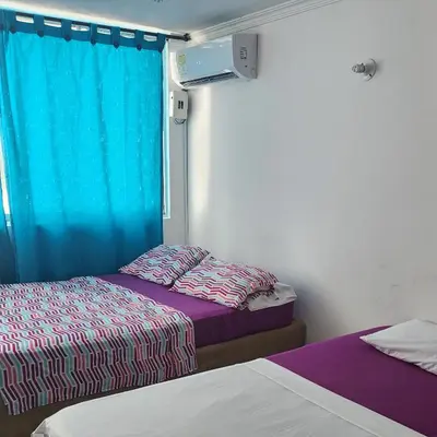 two beds in a room with a blue curtain at Arriendos Yeny in Cartagena de Indias