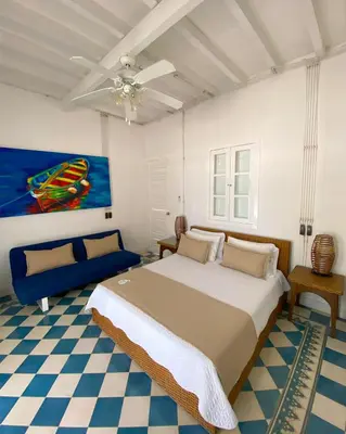 a bedroom with a large bed and a blue couch at Hotel Agua Azul Beach Resort in Baru