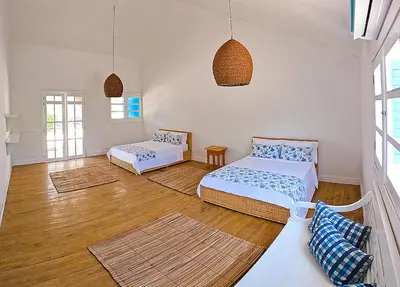 two beds in a room with wooden floors and windows at Hotel Agua Azul Beach Resort in Baru