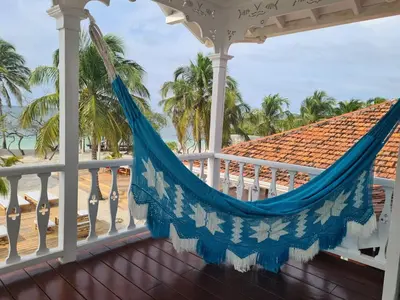 a hammock on a porch overlooking the beach at Hotel Agua Azul Beach Resort in Baru