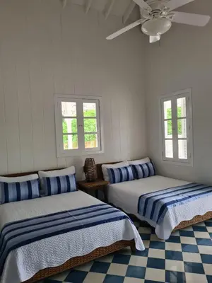 two beds in a white room with two windows at Hotel Agua Azul Beach Resort in Baru