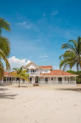 a large house on the beach with palm trees at Hotel Agua Azul Beach Resort in Baru