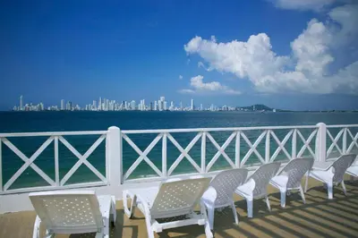 a row of chairs on a balcony overlooking the water at Hotel Dorado Plaza Punta Arena in Tierra Bomba