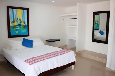 a bedroom with a bed with two paintings on the wall at Hotel Dorado Plaza Punta Arena in Tierra Bomba