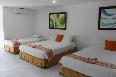 two beds in a room with white walls at Hotel Dorado Plaza Punta Arena in Tierra Bomba