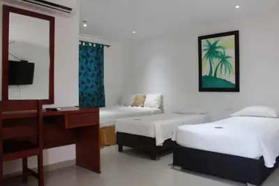 a bedroom with two beds and a desk and a mirror at Hotel Dorado Plaza Punta Arena in Tierra Bomba