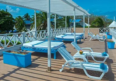 a deck with blue and white chairs and tables at Hotel Dorado Plaza Punta Arena in Tierra Bomba