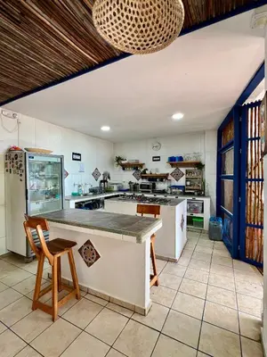 a large kitchen with a counter and chairs in it at Hostel Beach House in Rincón