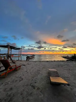 a beach with a bench and a boat in the water at Hostel Beach House in Rincón