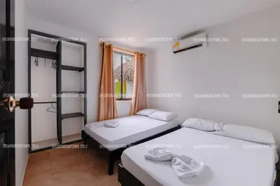 two beds in a room with a window at Caribbean Town Tolu in Tolú