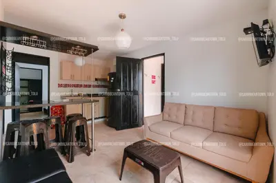 a living room with a couch and a kitchen at Caribbean Town Tolu in Tolú