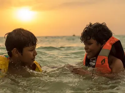 two young boys in the water at the beach at Raw KokoMar CasaNativa in Baru